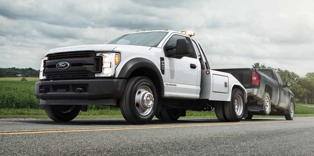 Ford Super Duty Chassis pulling a vehicle down the road for assistance