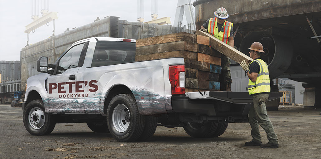 Ford Super Duty pickup with company logo and information printed on the doors.